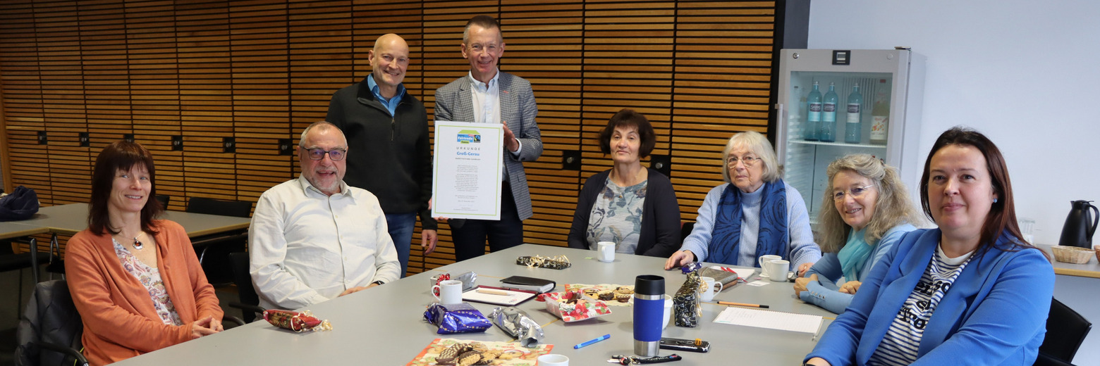 Bei der vergangenen Sitzung der Steuerungsgruppe waren dabei (sitzend von links) Claudia Weller (für die Steuerungsgruppe Büttelborn), Wolfgang Bleith (für die Steuerungsgruppe Bischofsheim), Barbara Reis (1. Vorsitzende Partnerschaft Eine Welt - Dornheim 1980 e. V., Betreiber des Weltladens Dornheim), Else Trumpold (Vorsitzende Kirchenvorstand Evangelische Kirchengemeinde Büttelborn), Karin Wehner (Fairtrade-Beauftragte Bischofsheim), Marta Wachowiak (Fachdienstleitung Klimaschutz Kreis GG), stehend links Stefan Leimbach (Fairtrade-Beauftragter des Kreises Groß-Gerau) und Landrat Thomas Will mit der Urkunde zur Titelerneuerung. Foto: Kreisverwaltung